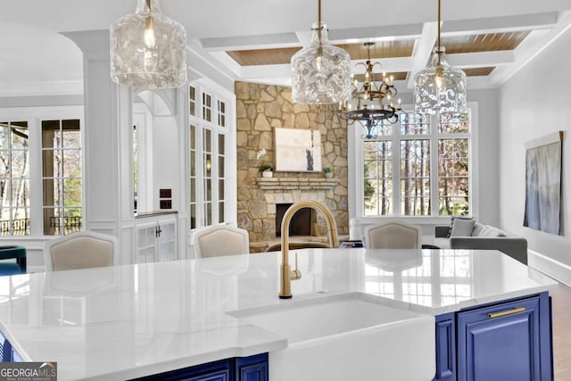 kitchen with beam ceiling, a fireplace, a sink, blue cabinets, and open floor plan