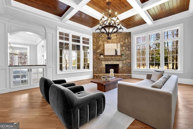 living room featuring wood finished floors, a stone fireplace, a chandelier, and wooden ceiling