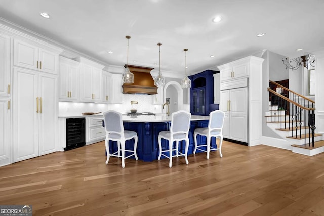 kitchen with wine cooler, custom exhaust hood, wood finished floors, and white cabinetry