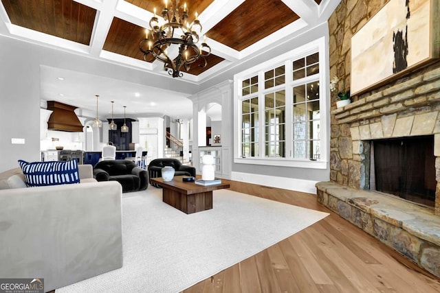 living area with an inviting chandelier, wood finished floors, a fireplace, and coffered ceiling