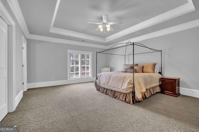 bedroom with baseboards, a tray ceiling, ornamental molding, carpet flooring, and a ceiling fan