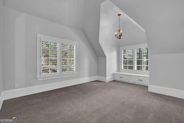 additional living space featuring vaulted ceiling, baseboards, an inviting chandelier, and dark colored carpet