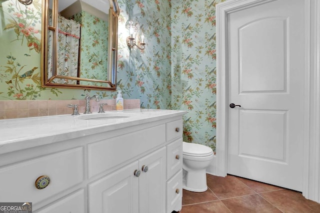 bathroom with wallpapered walls, toilet, vanity, and tile patterned flooring