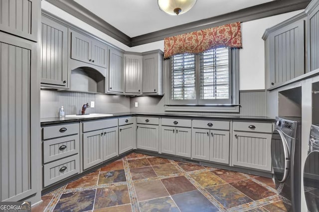 kitchen with a sink, dark countertops, gray cabinetry, and crown molding