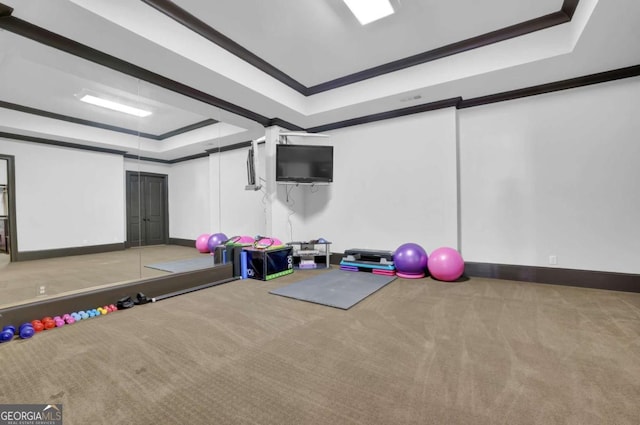 workout area with carpet flooring, a raised ceiling, baseboards, and ornamental molding