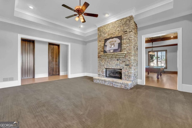 unfurnished living room featuring visible vents, a fireplace, crown molding, a raised ceiling, and carpet flooring