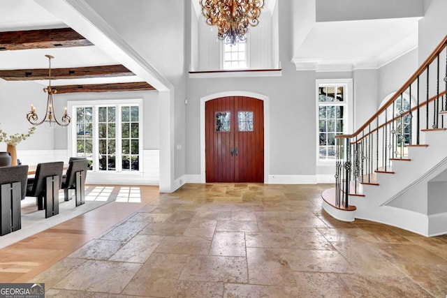 entrance foyer featuring a chandelier, a healthy amount of sunlight, stairs, and stone tile flooring