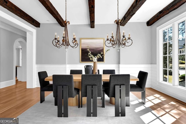 dining room with arched walkways, a notable chandelier, wainscoting, and wood finished floors