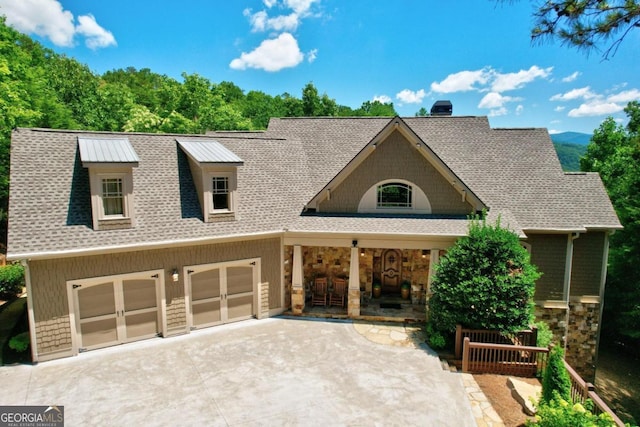 view of front of home with a garage, concrete driveway, roof with shingles, and stone siding