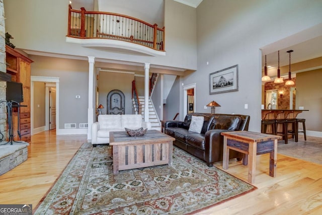 living room with ornamental molding, a high ceiling, wood finished floors, and baseboards