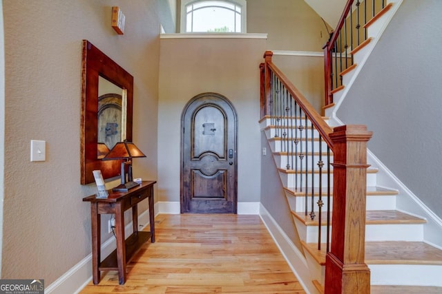 entrance foyer with a towering ceiling, baseboards, and wood finished floors