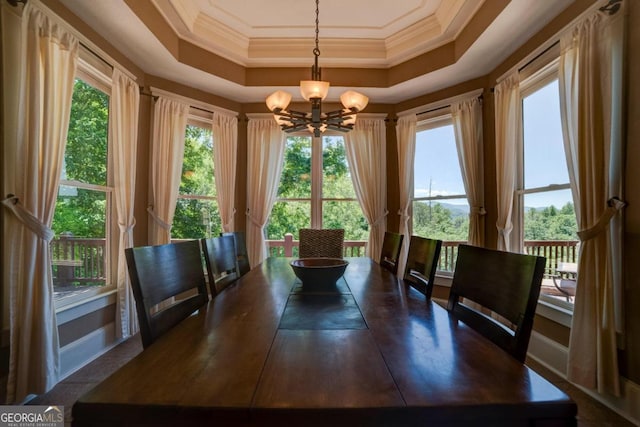 unfurnished dining area featuring a chandelier, a raised ceiling, and crown molding