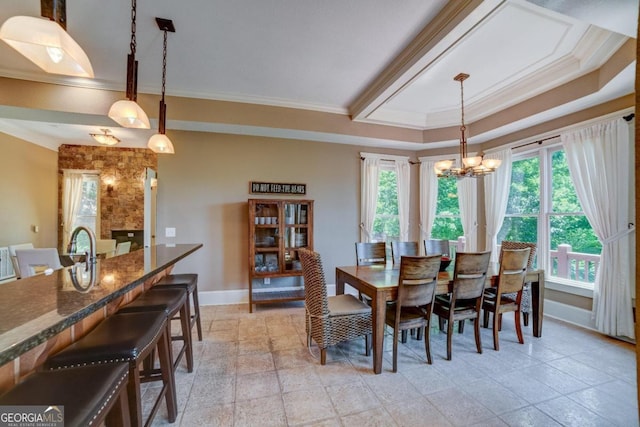 dining room featuring ornamental molding, a tray ceiling, a notable chandelier, and baseboards