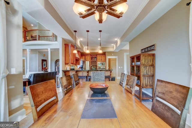 dining area featuring decorative columns, baseboards, light wood-style flooring, and crown molding