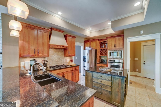 kitchen featuring a sink, appliances with stainless steel finishes, custom exhaust hood, a tray ceiling, and tasteful backsplash