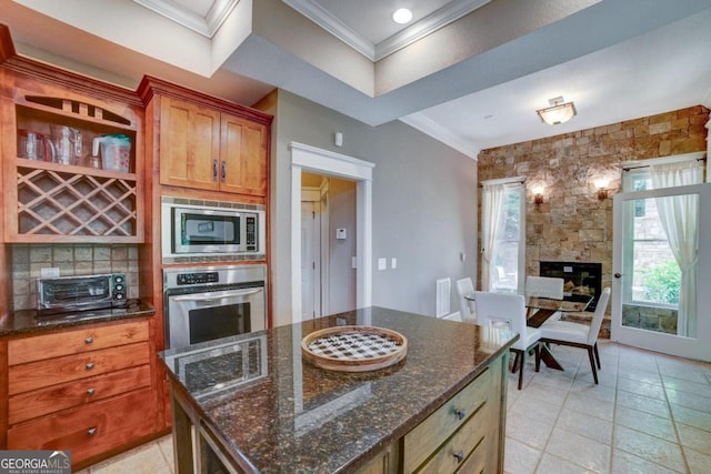 kitchen with a toaster, appliances with stainless steel finishes, backsplash, dark stone counters, and crown molding