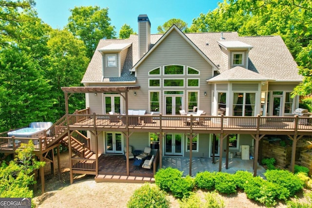 rear view of house with a shingled roof, french doors, a chimney, a wooden deck, and a patio area