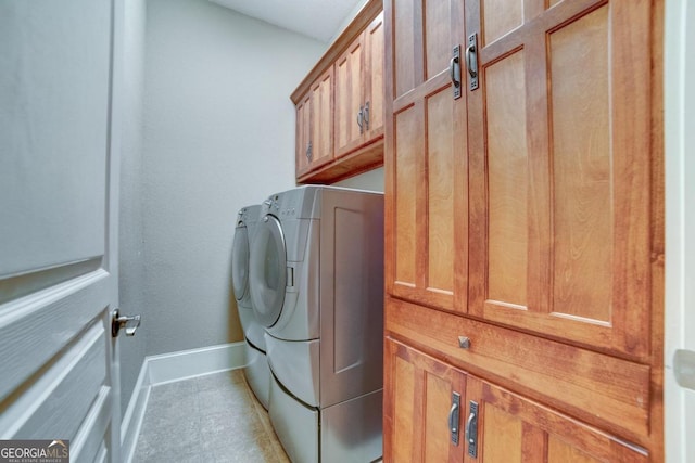 washroom with washer and dryer, cabinet space, and baseboards