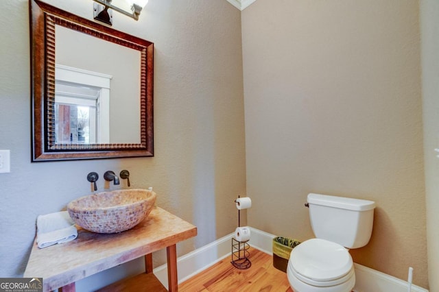 bathroom with toilet, baseboards, and wood finished floors