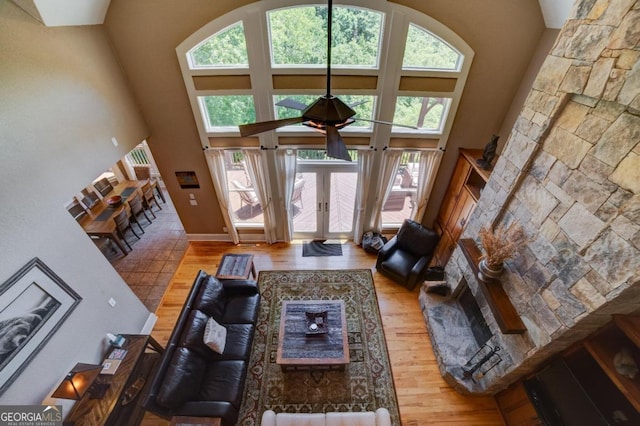 living area with french doors, wood finished floors, and a towering ceiling