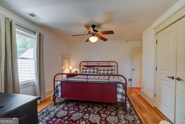 bedroom featuring baseboards, light wood-style flooring, visible vents, and a ceiling fan