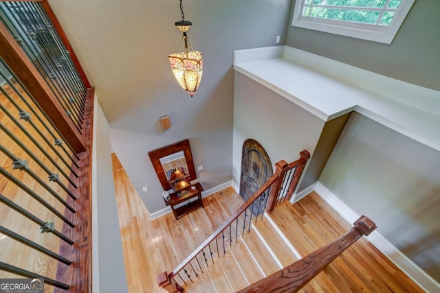 stairs featuring an inviting chandelier, wood finished floors, and baseboards