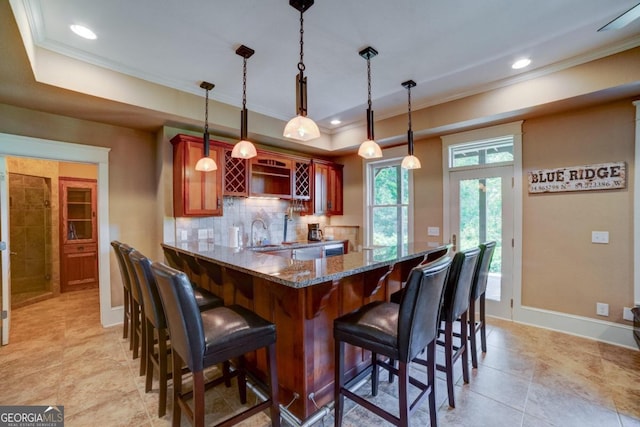 kitchen featuring tasteful backsplash, a tray ceiling, crown molding, and decorative light fixtures