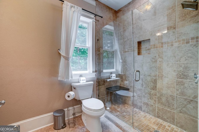 full bath featuring toilet, plenty of natural light, a shower stall, and baseboards