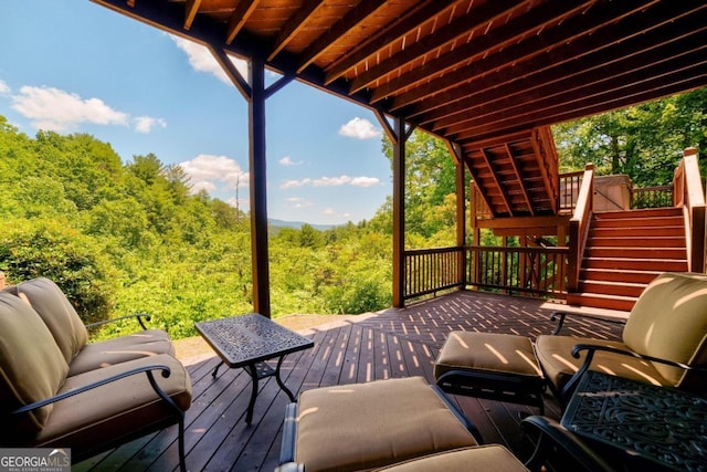 wooden terrace featuring stairs and a wooded view