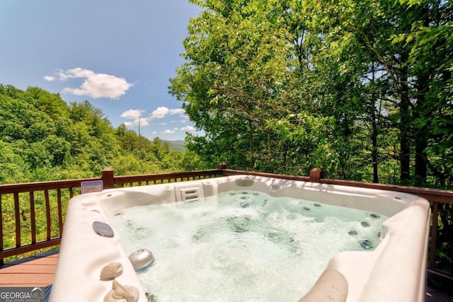 deck featuring a forest view and a hot tub