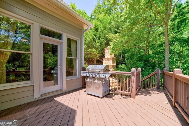 deck with a fireplace and area for grilling