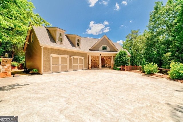 view of front facade featuring driveway, a shingled roof, and a garage