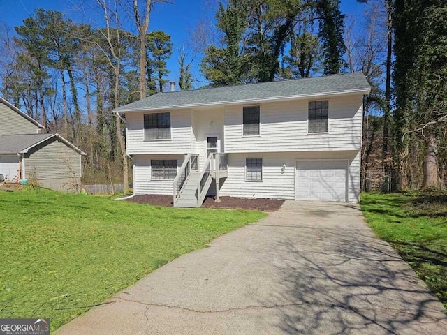 raised ranch featuring an attached garage, driveway, and a front lawn