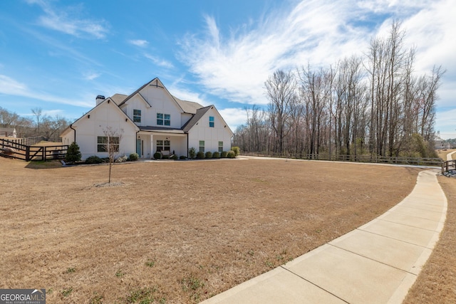 view of front facade featuring a chimney, fence, a front lawn, and board and batten siding