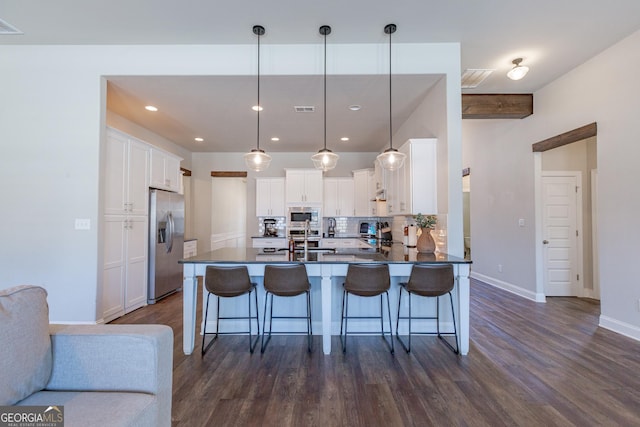 kitchen featuring dark countertops, decorative backsplash, appliances with stainless steel finishes, a peninsula, and a kitchen breakfast bar