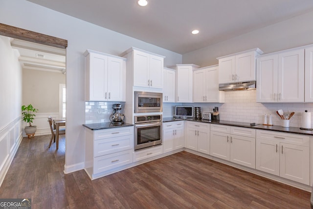 kitchen featuring dark countertops, under cabinet range hood, appliances with stainless steel finishes, and dark wood-style flooring