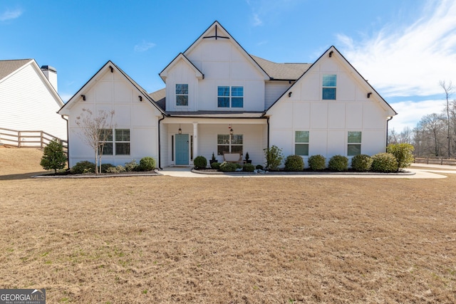 modern inspired farmhouse with a front yard, roof with shingles, and fence