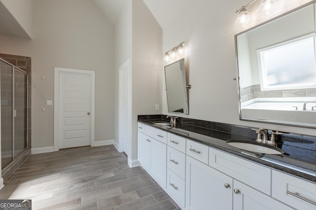 full bathroom featuring a stall shower, a sink, wood tiled floor, and double vanity