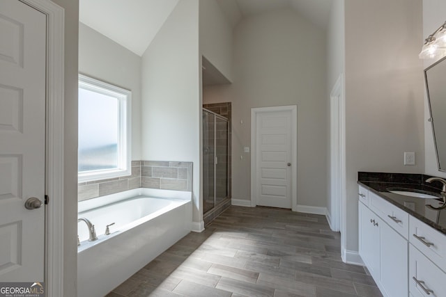 full bathroom featuring high vaulted ceiling, a garden tub, wood finish floors, vanity, and a stall shower