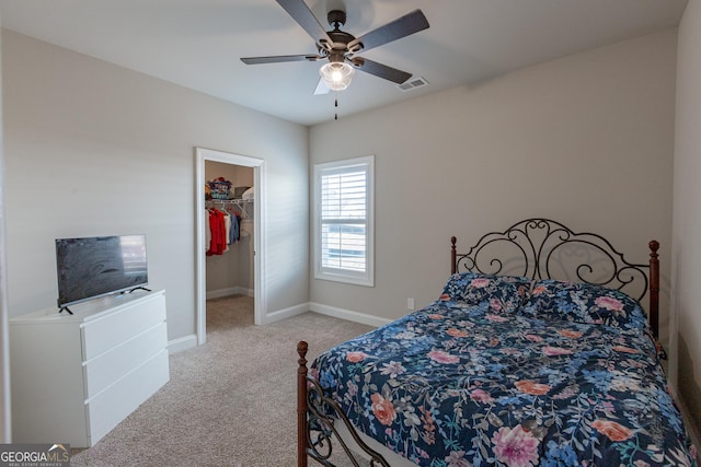 bedroom with visible vents, a spacious closet, light carpet, ceiling fan, and baseboards