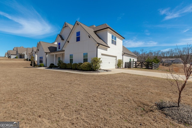 view of home's exterior with a garage, driveway, fence, and a shingled roof