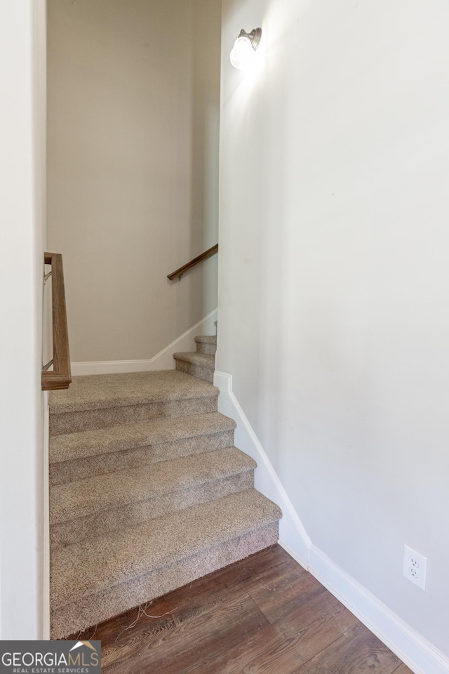 staircase with baseboards and wood finished floors