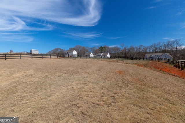 view of yard with fence, an enclosed area, an outbuilding, and a rural view