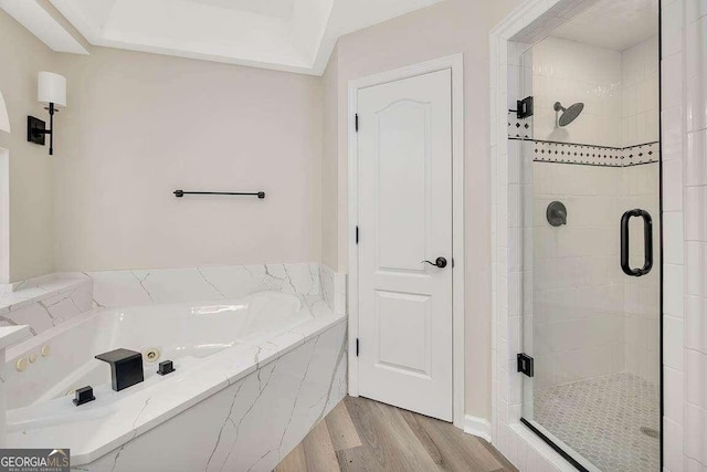 bathroom featuring a garden tub, wood finished floors, and a shower stall