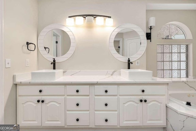 bathroom featuring a garden tub, double vanity, and a sink