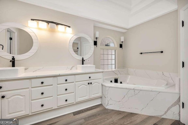 full bath with wood finished floors, a sink, a bath, and double vanity