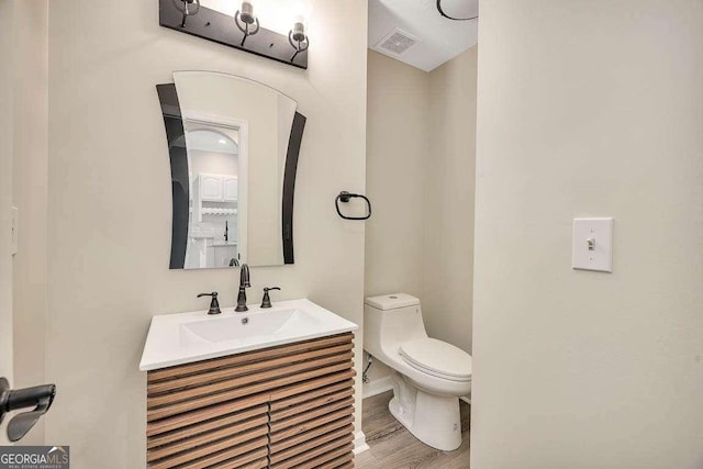 bathroom with visible vents, vanity, toilet, and wood finished floors