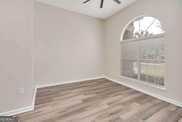 spare room with wood finished floors, a ceiling fan, and baseboards