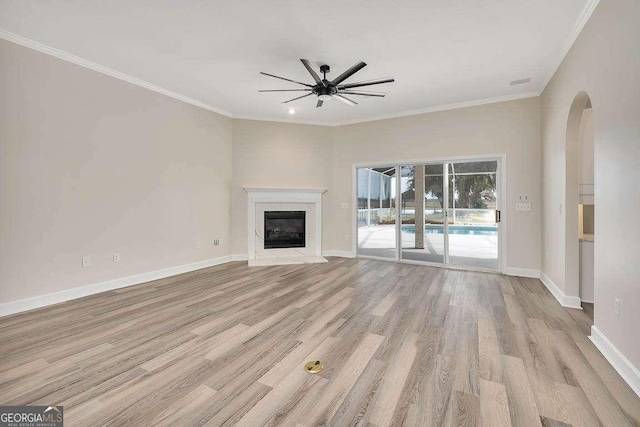 unfurnished living room with ornamental molding, a fireplace, baseboards, and wood finished floors