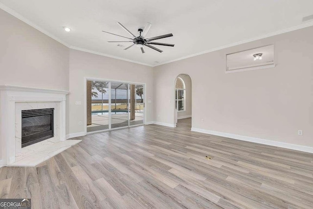 unfurnished living room featuring baseboards, a ceiling fan, ornamental molding, wood finished floors, and a high end fireplace